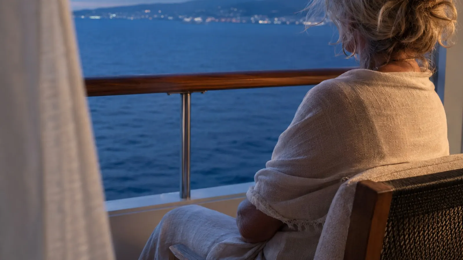 Voyageuse seule assise sur le balcon d’une cabine face à la mer