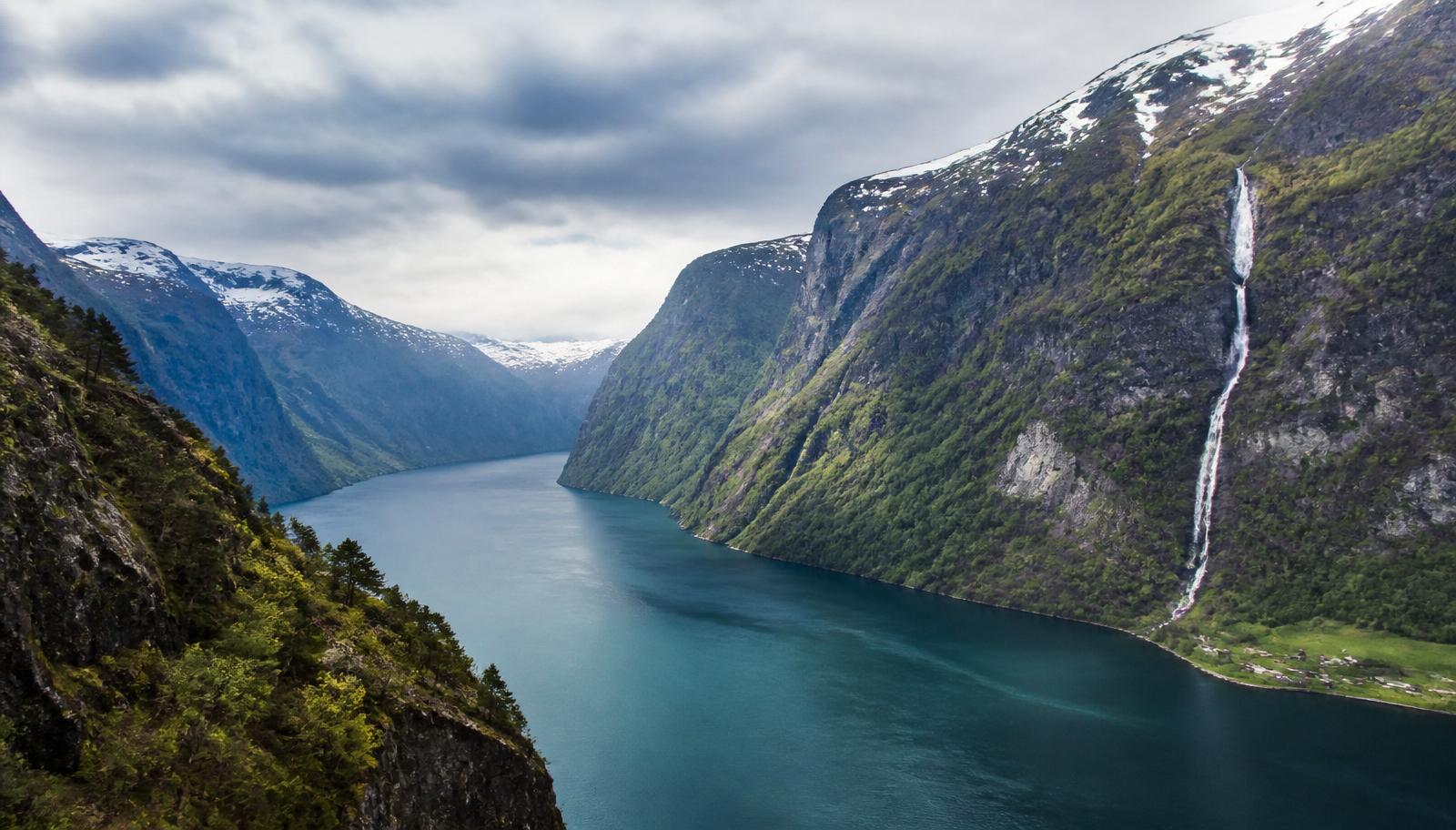 Vue plongeante sur un fjord norvégien profond bordé de falaises et d’une cascade