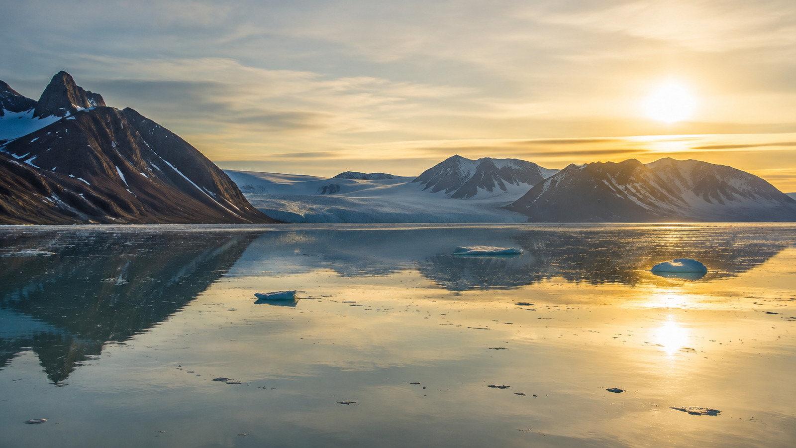 Fjord arctique du Svalbard aux eaux calmes reflétant des montagnes découpées sous le soleil de minuit